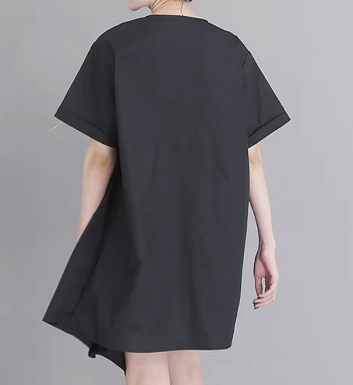 Light pink DIGS poplin pleated short dress with a fitted bodice and flowing skirt, shown from the back.