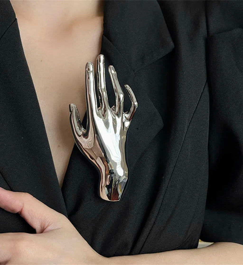 Silver DIGS hand-shaped brooch, decorative jewelry accessory with detailed craftsmanship and elegant design.